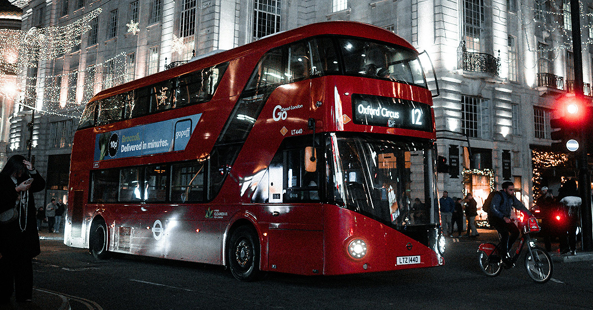 red public bus on a London street at night