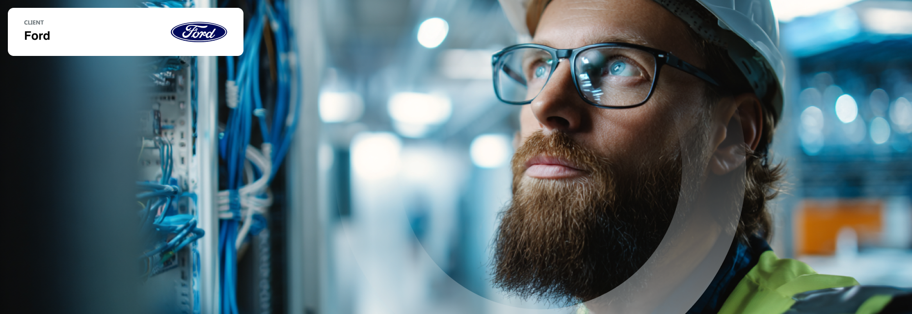 Close-up of a man with glasses and a hard hat looking up at server cabling in a data center.